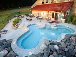 Relax by the unique, curved pool surrounded by a deck and rocks, with comfortable seating areas for socializing or unwinding.