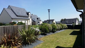 A residential area with houses, a paved pathway, and a street lamp. - Luxueuse villa, piscine intérieure, plage à 700m (Saint Coulomb)