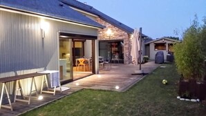 A modern house with a patio, a dining area, and a covered outdoor seating area. - Luxueuse villa, piscine intérieure, plage à 700m (Saint Coulomb)