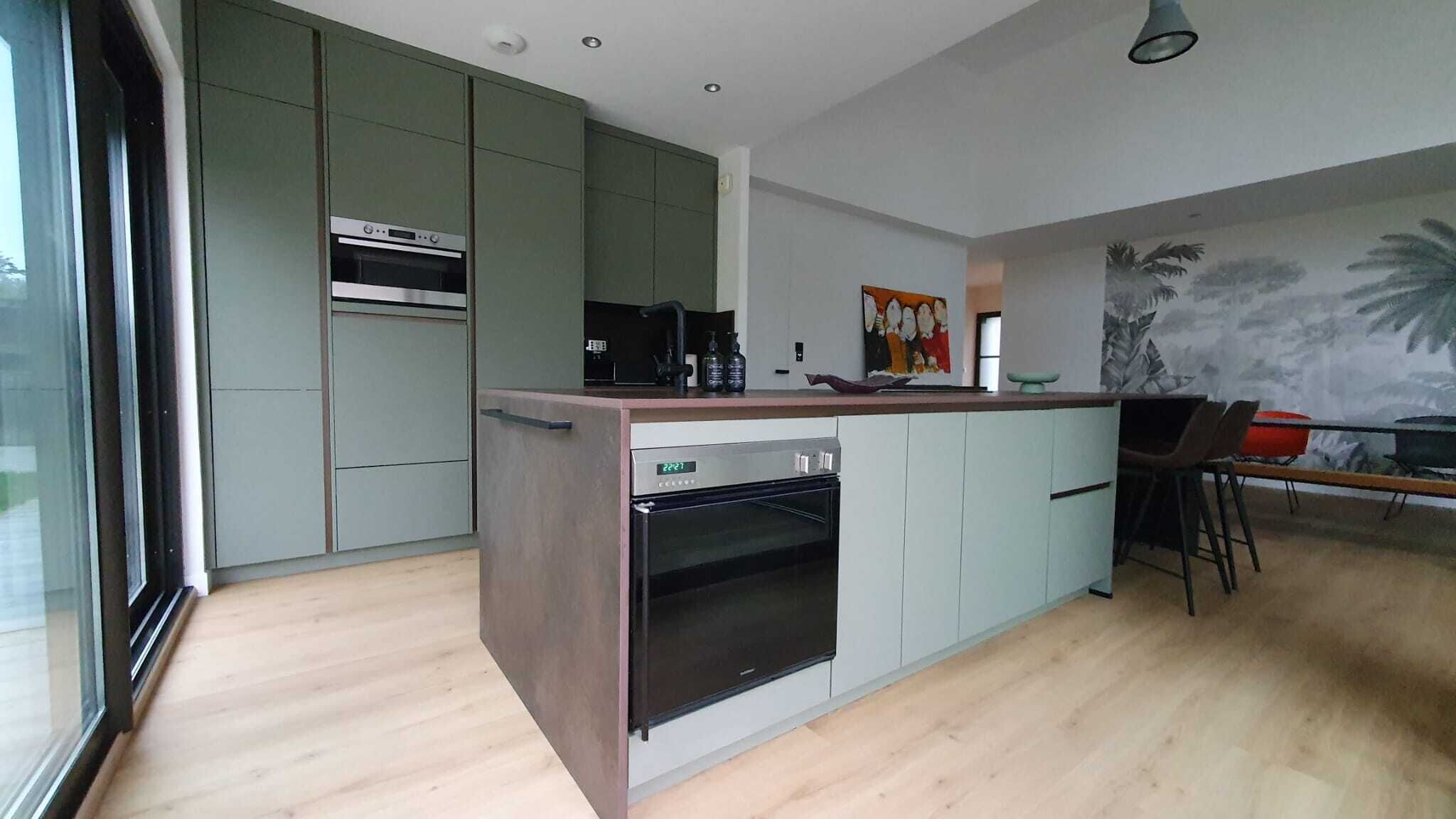 A modern kitchen with built-in appliances, a dining area with a mural, and a large window.