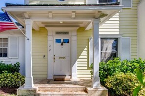 A house with a white front door, a porch with a white railing, and a small step leading up to the door.