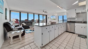 A modern kitchen with white cabinets, a granite countertop, and a dishwasher. - Island Winds West 580 | Walk to HangOut! | Heated Pool! | Beach Getaways (Gulf Shores)