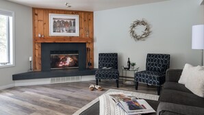A living room with a fireplace, two patterned chairs, a sofa, and a magazine on a coffee table. - Outpost: Balsam Lodge A3 - Aspens Location! (Wilson)