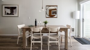 A dining area with a wooden table, white chairs, a hanging light fixture, and wall-mounted artwork. - Outpost: Balsam Lodge A3 - Aspens Location! (Wilson)