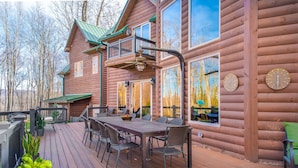 Eine Holzhütte mit einer Veranda, Sitzgelegenheiten im Freien und großen Fenstern.