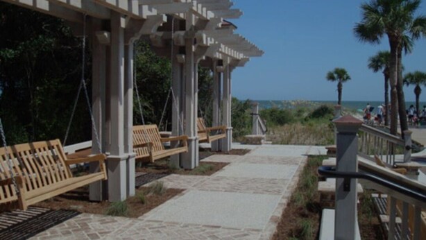 A covered walkway with benches, palm trees, and a view of the beach. - Condo Near Coligny Circle, Beach, & New Park; all within 1 to 2 Blocks (Hilton Head Island)