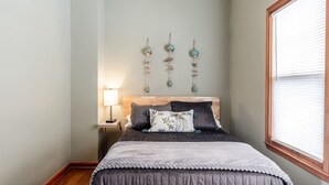 Un dormitorio con una cama, una mesita de noche, una lámpara y adornos en la pared.