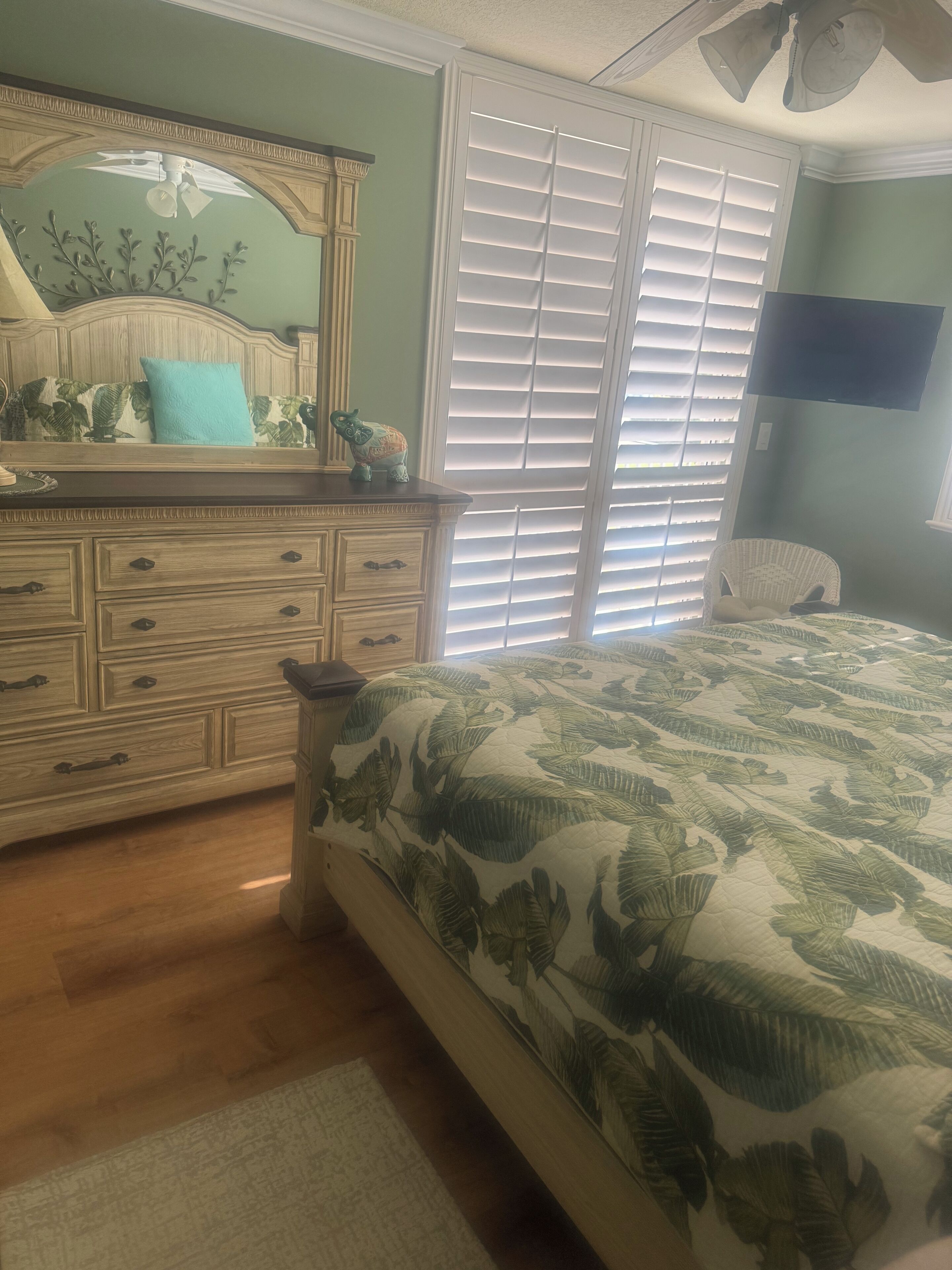 A bedroom with a bed, dresser, and a large window with blinds.