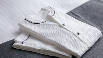 Una camisa blanca doblada con ribete negro sobre una superficie gris.