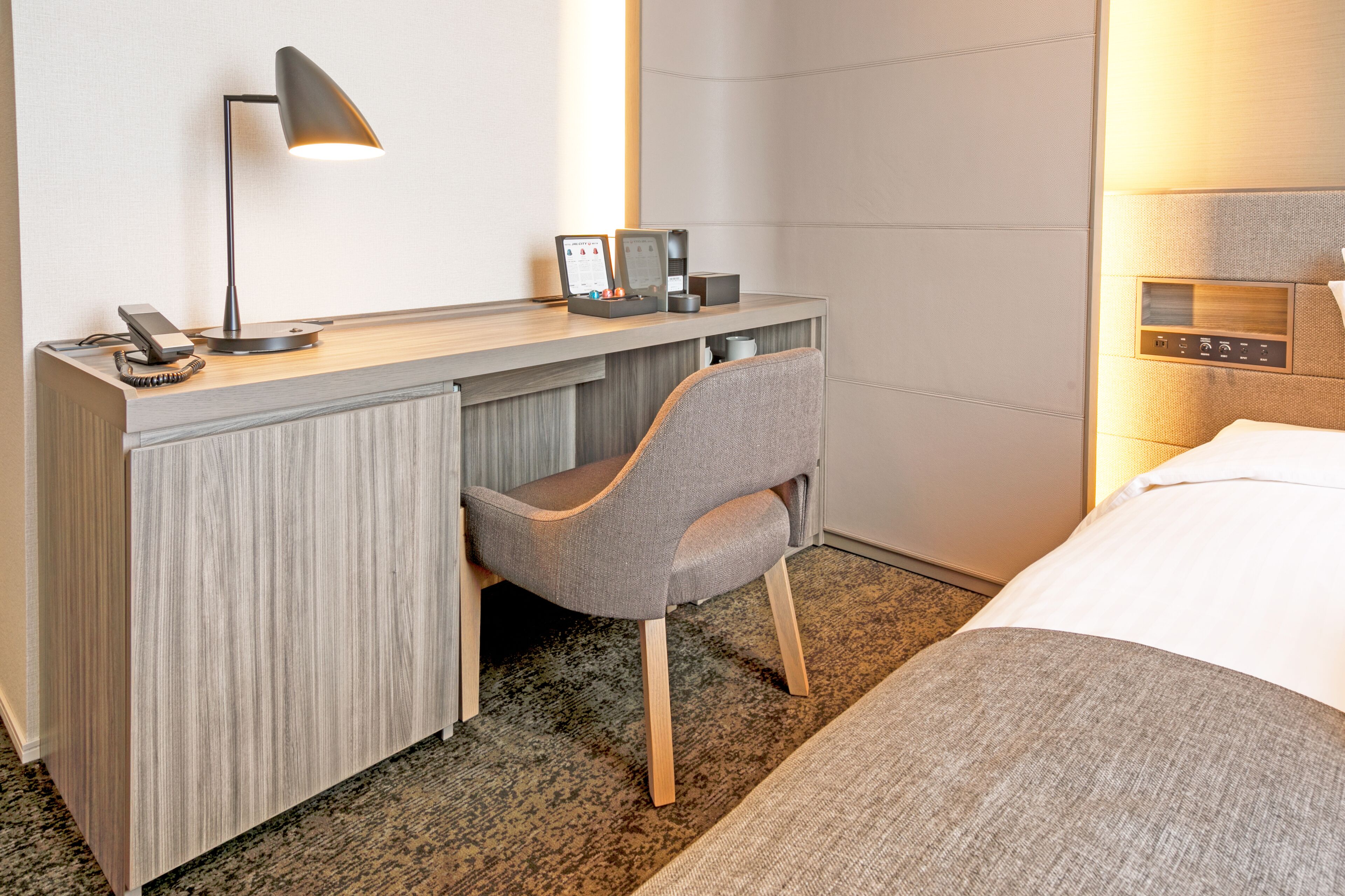 A hotel room with a desk, chair, and bed.