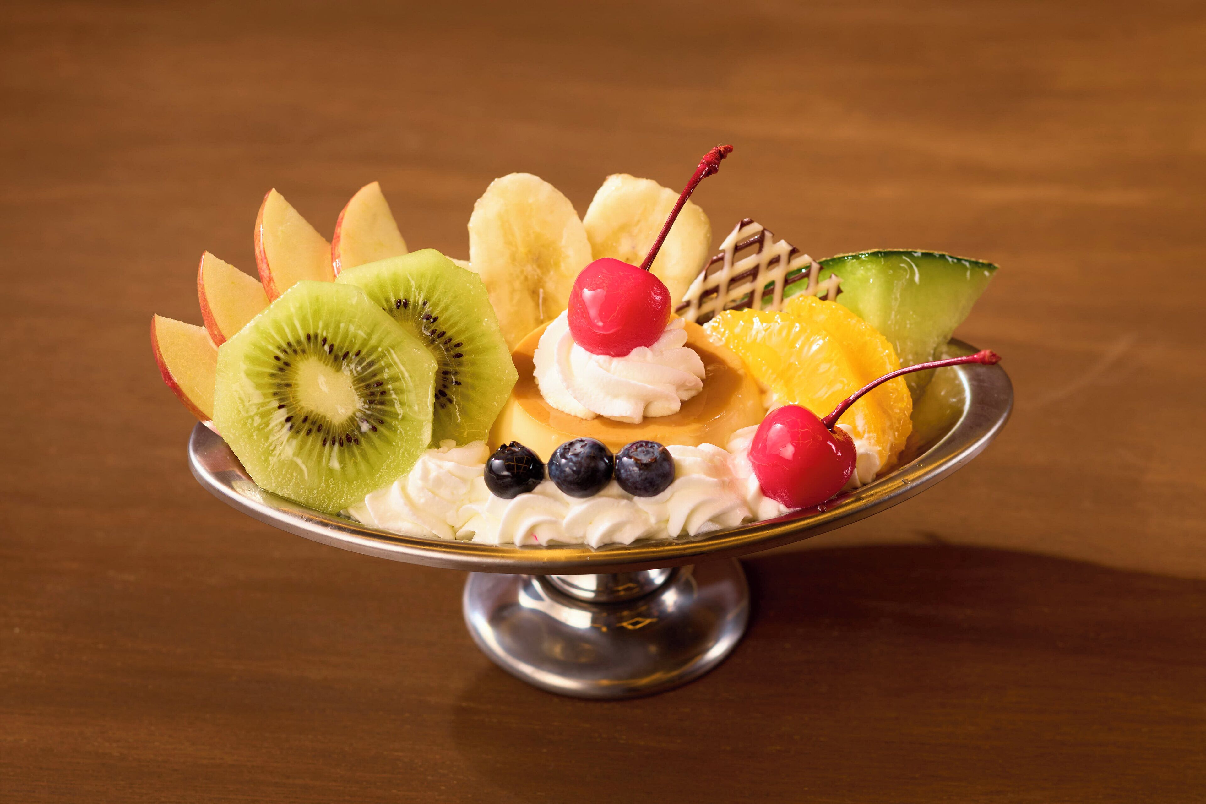 A dessert with various fruits and a cherry on top.