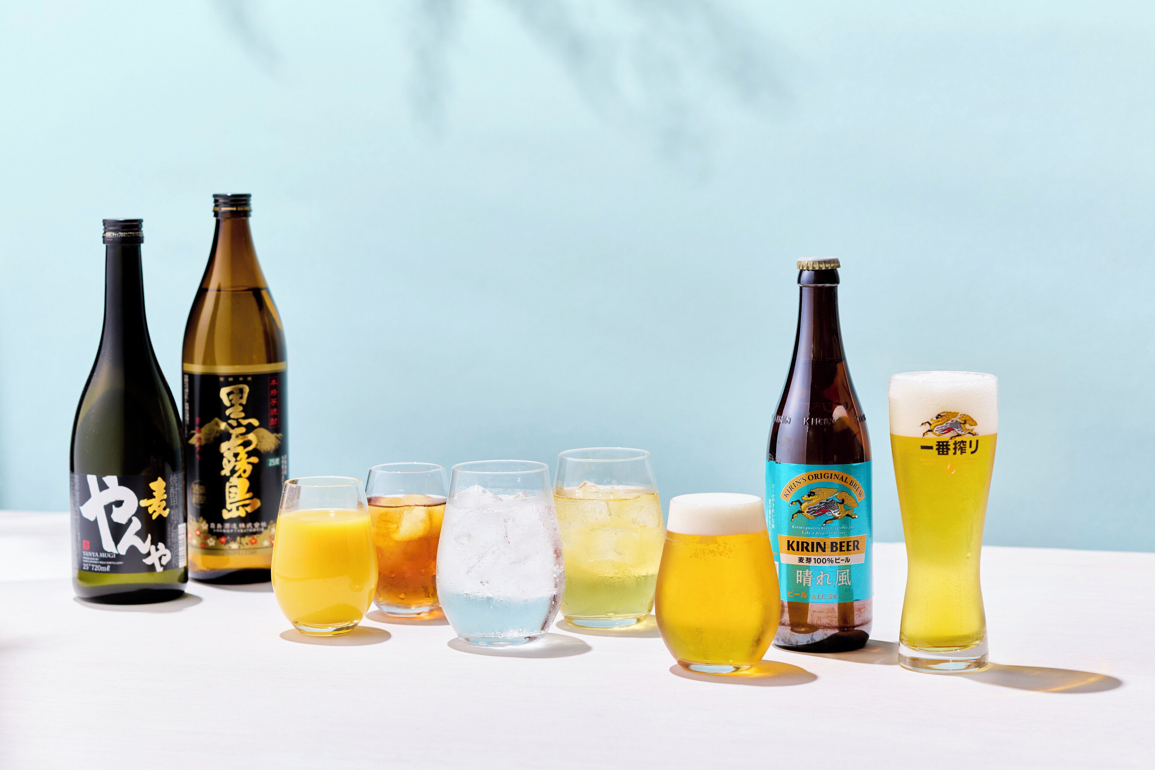 Eine Auswahl an Getränken, darunter Bier und Sake, präsentiert auf einem Tisch vor hellem Hintergrund.