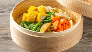 A round bamboo steamer filled with various vegetables.