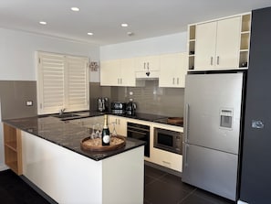A modern kitchen with a central island, built-in appliances, and a water dispenser. - Snowman 3 Luxury stay Central Village & Parking. (Thredbo)