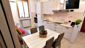 Een moderne keuken met witte kasten, een inbouwoven en een groot raam.