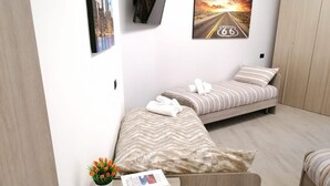 Een moderne hotelkamer met twee bedden, een klein tafeltje met een boek en een bloevas, en een schilderij van een weg aan de muur.
