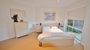Un dormitorio con cama, cómoda, mesita de noche, lámpara y un cuadro en la pared.