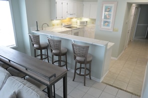 Una cocina con una isla central, taburetes de bar y una mesa de comedor.