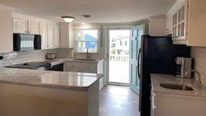 A modern kitchen with white cabinetry, a black refrigerator, and a large island.