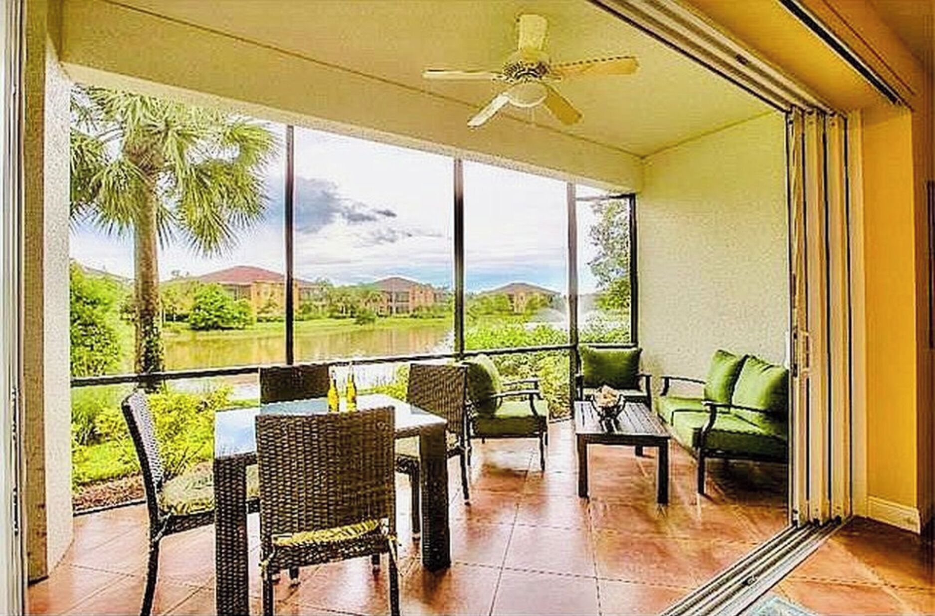 A balcony with a table and chairs, a sofa, and a view of a lake and greenery.