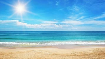 Une plage avec un ciel dégagé et une mer calme.