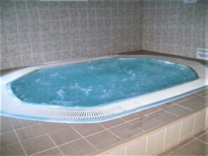 Un jacuzzi rectangular con borde texturizado, rodeado de paredes con azulejos.