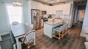 A modern kitchen with white cabinets, stainless steel appliances, and a central island with bar stools.