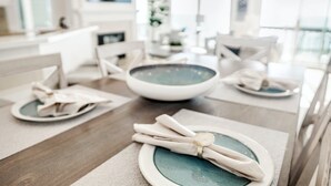 Een eettafel gedekt met borden, kommen en opgevouwen servetten.