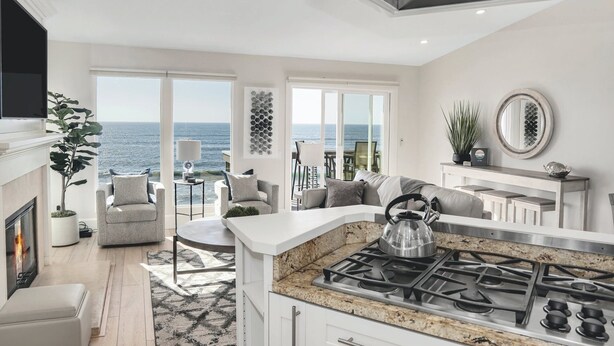 Een moderne keuken met een gasfornuis, een eethoek met uitzicht op zee, en een gezellige zithoek met open haard.