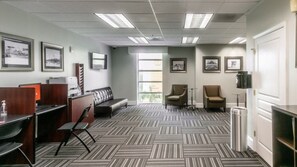 Une chambre d’hôtel équipée d’un bureau, de deux chaises, d’un canapé, d’une poubelle et de tableaux encadrés aux murs.