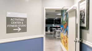 A hallway leading to an activities center and fitness studio, with a sign indicating the direction.