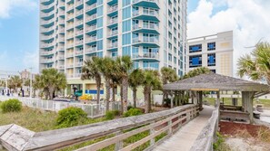 A multi-story hotel with balconies, a wooden boardwalk, and a gazebo.