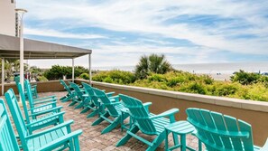 A terrace with turquoise chairs and a view of the beach.
