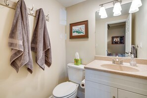 Un baño con inodoro, lavabo y toallas colgadas en un perchero.