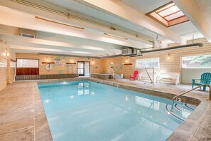 Una piscina interior con suelo de baldosas, un trampolín y una zona de bancos.