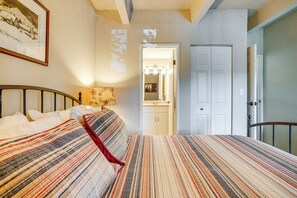 Un dormitorio con cama, mesita de noche, lámpara y puerta que da a un baño.