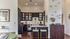 A modern kitchen with dark cabinets, a central island, and stools.