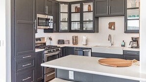 A modern kitchen with dark cabinets, stainless steel appliances, and a central island.