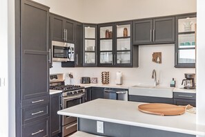 Une cuisine moderne avec des meubles de couleur sombre, des appareils en acier inoxydable et un îlot central.