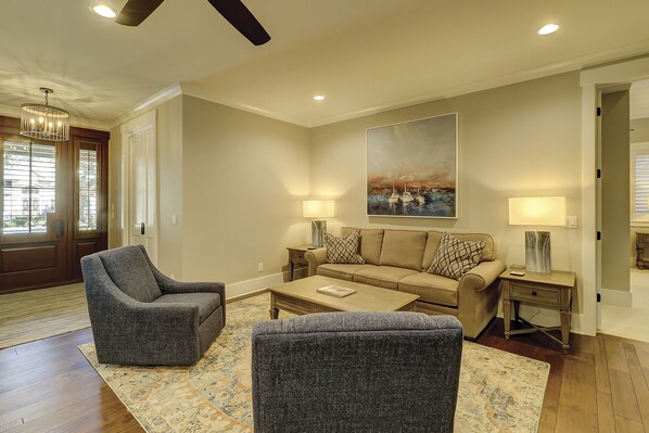 A living room with a sofa, two armchairs, a coffee table, and a painting on the wall.