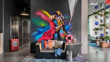 Een hal met een kleurrijke muurschildering, een houten bank, een rode koffer en een modern interieur.