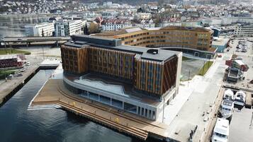 Un edificio moderno con fachada curva, un muelle frente al agua y un estacionamiento con barcos.