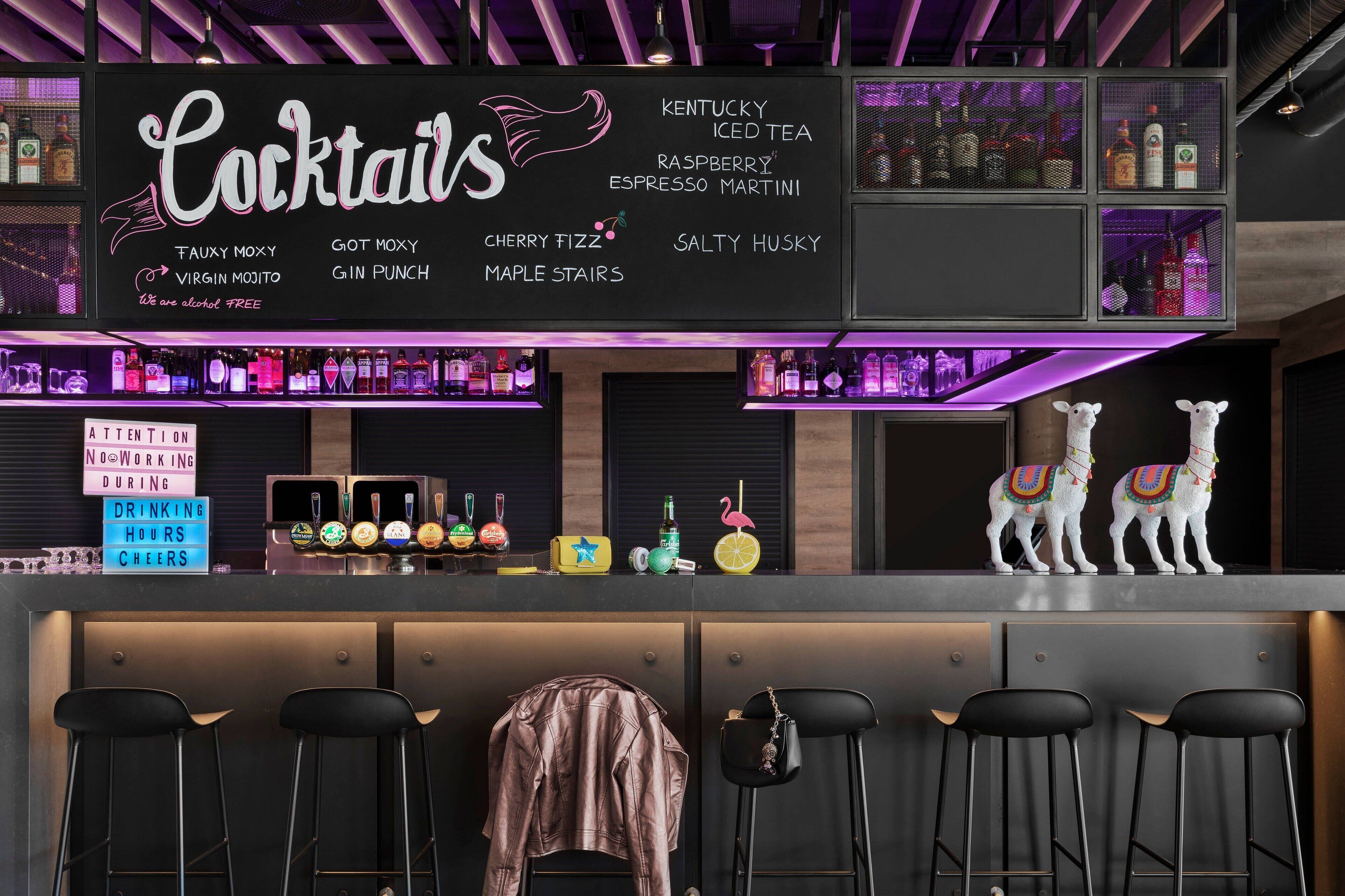 Zona de bar con un menú que ofrece cócteles y un cartel que indica que no se permite trabajar durante el horario de consumo.