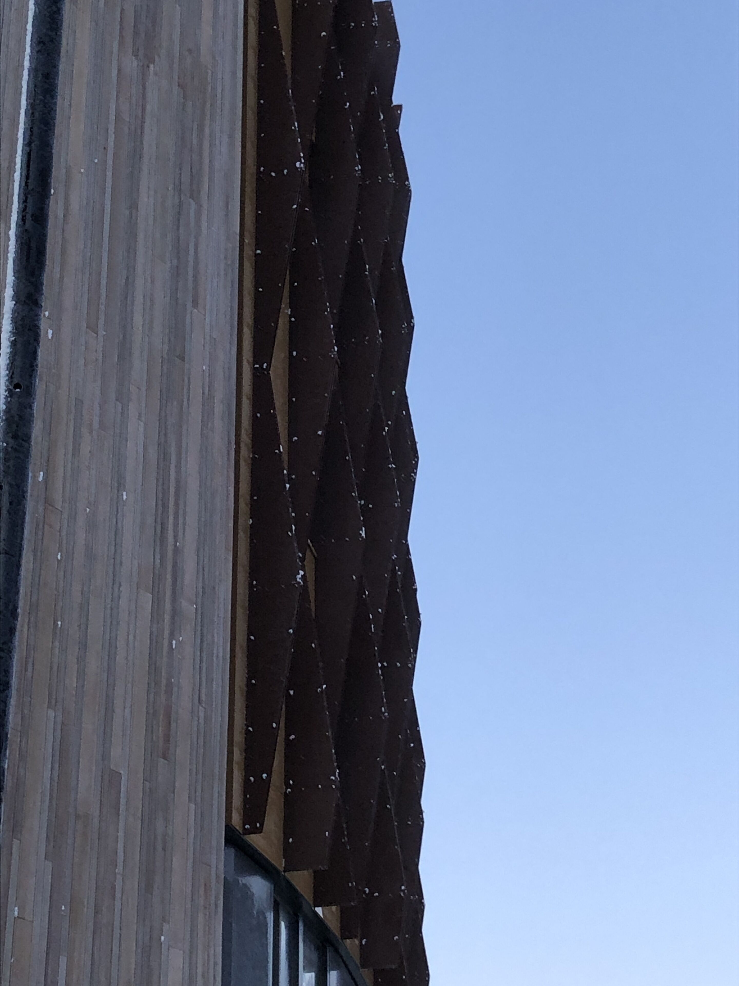 Un edificio con fachada de madera y paneles de metal corrugado.