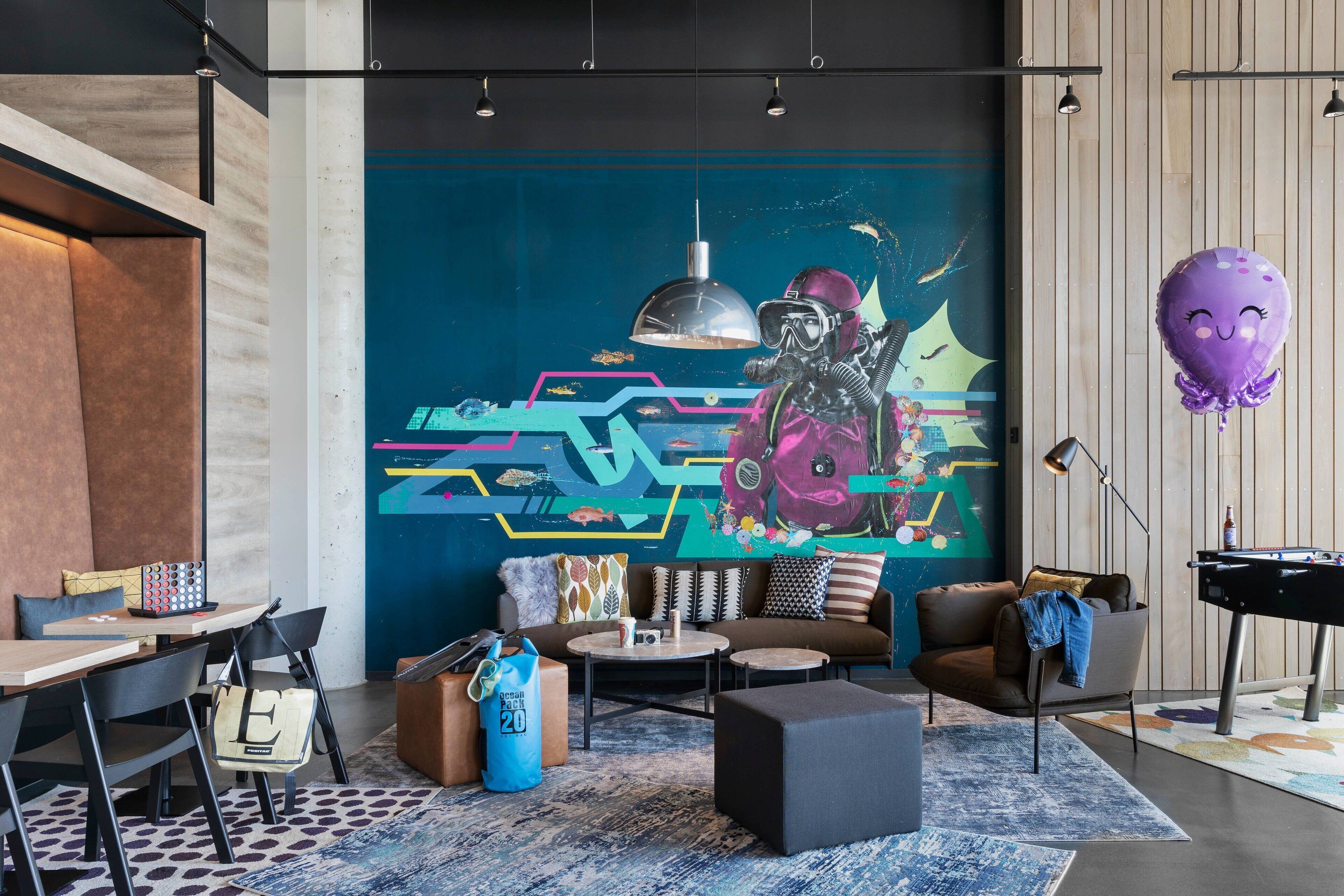 Una sala de estar moderna con un mural, mesa de billar y asientos cómodos.