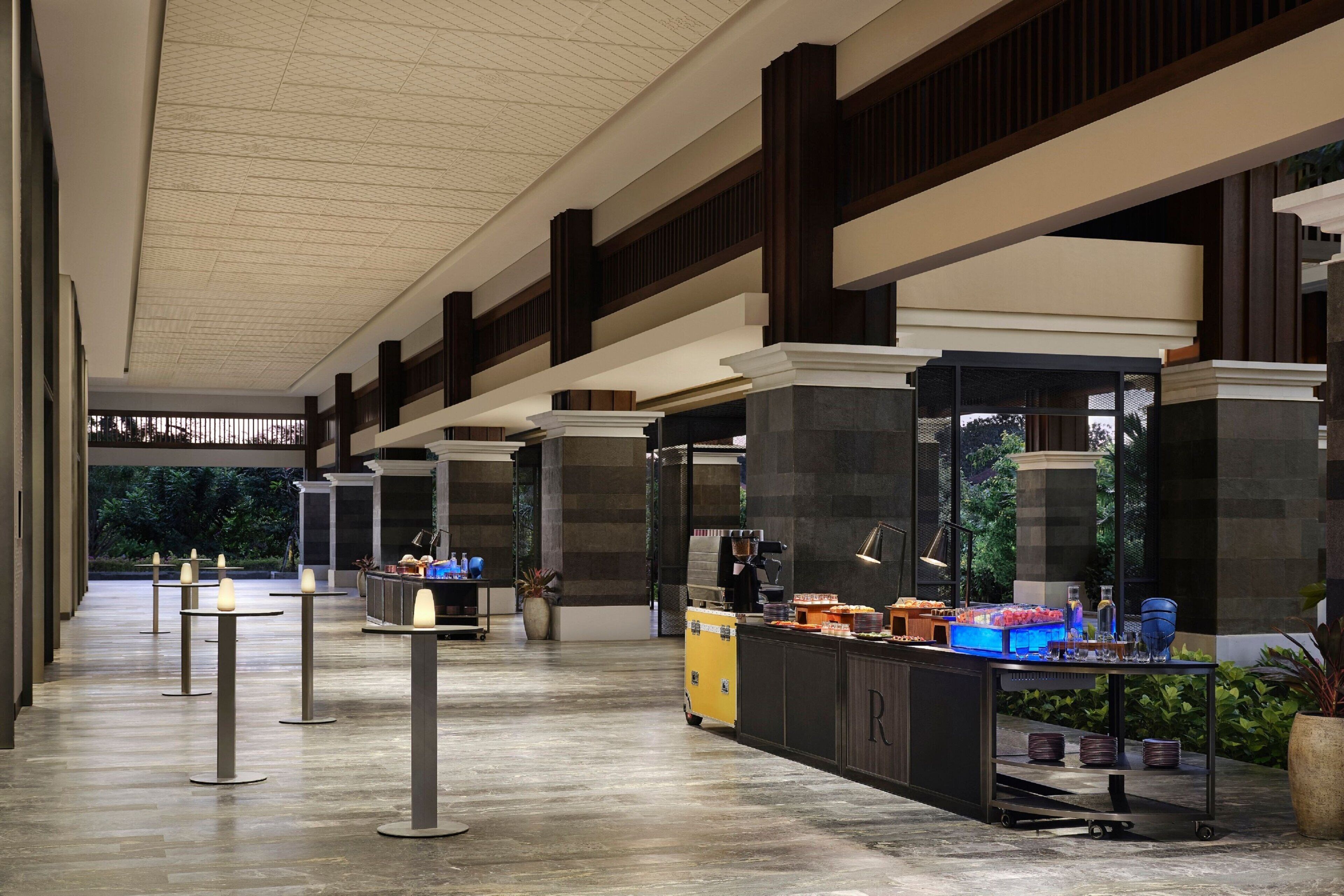 Un hall d’entrée spacieux avec un plafond haut, plusieurs niveaux et un bar central offrant toute une gamme de services.