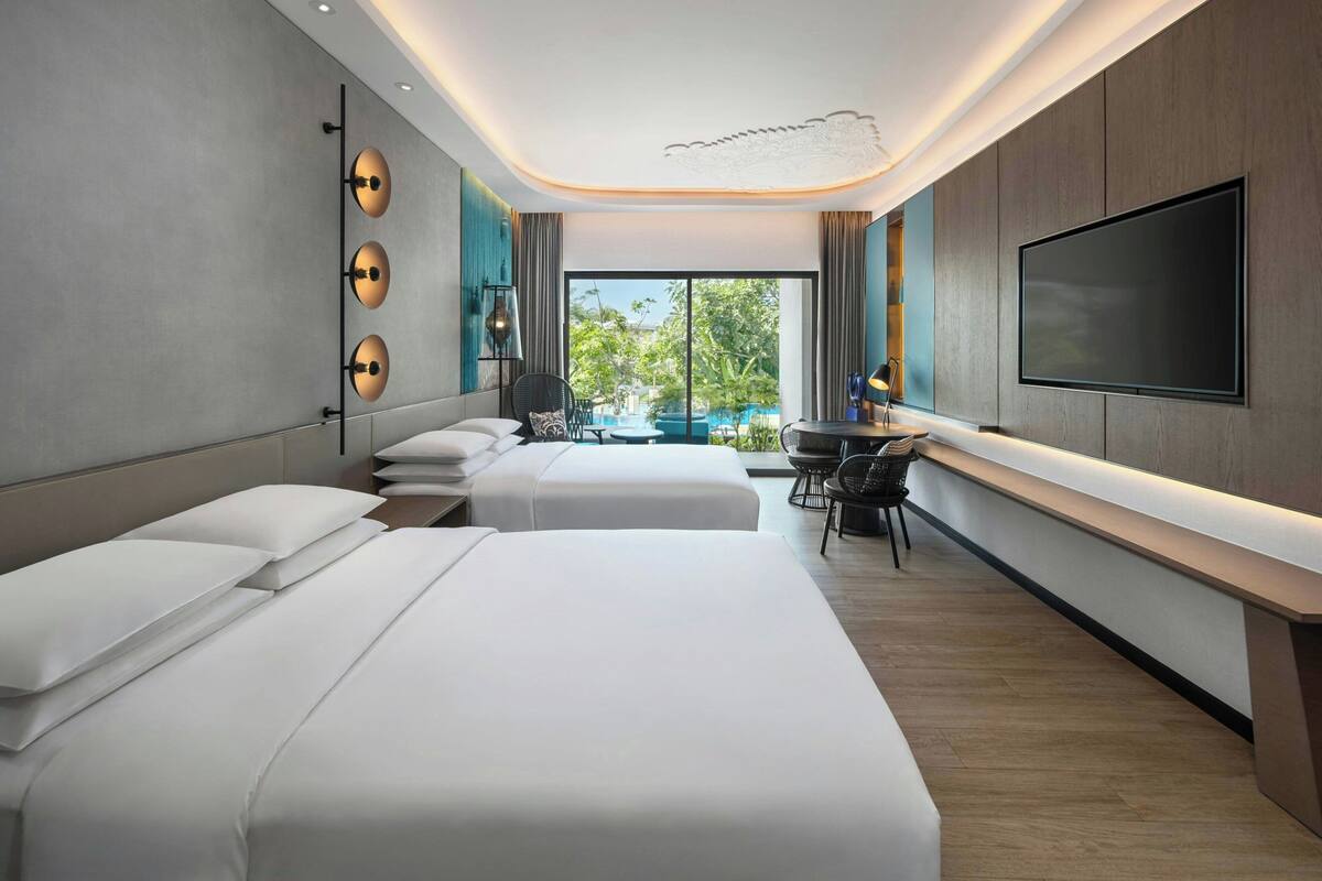 Habitación de hotel con dos camas, un escritorio, un televisor de pantalla plana y vista al exterior.