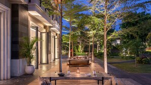 Un espacio al aire libre con mesa y bancos de madera, rodeado de follaje y árboles.