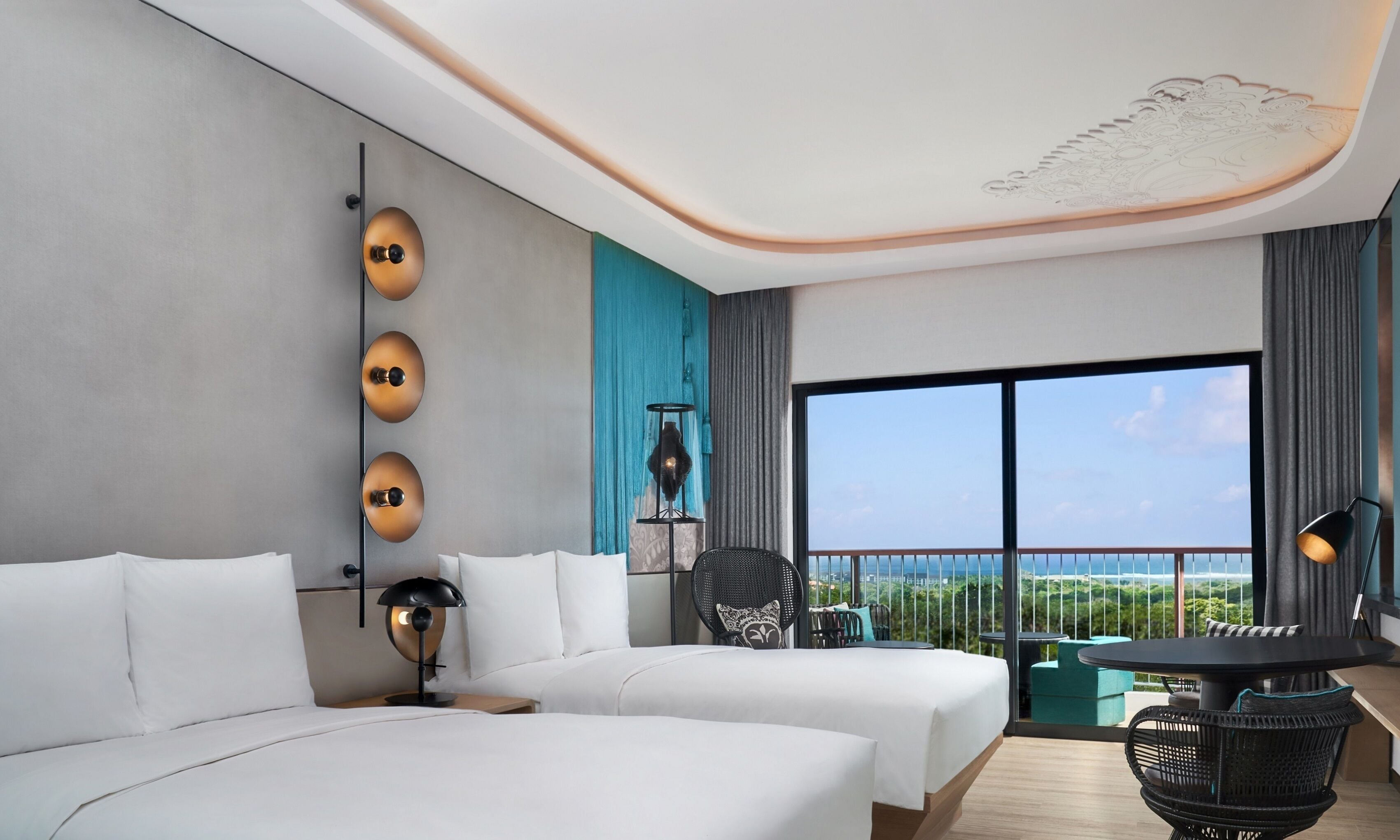 A hotel room with two beds, a balcony with a table and chairs, and a large window offering a view.