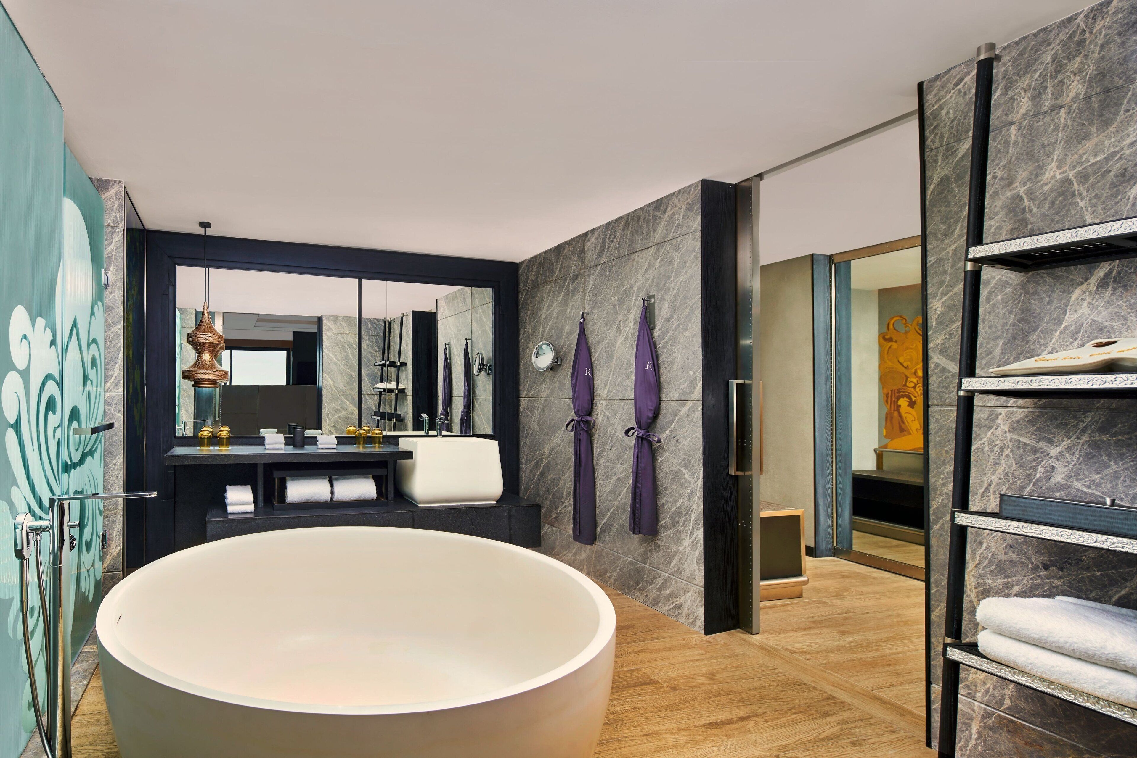 Une salle de bain moderne avec une grande baignoire, un meuble-lavabo avec un miroir et un porte-serviettes.